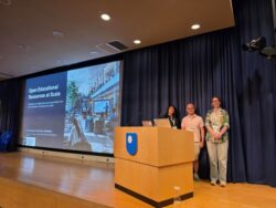 Dal, Benjamin and Kirstine standing behind a lectern in a lecture theatre at OER26